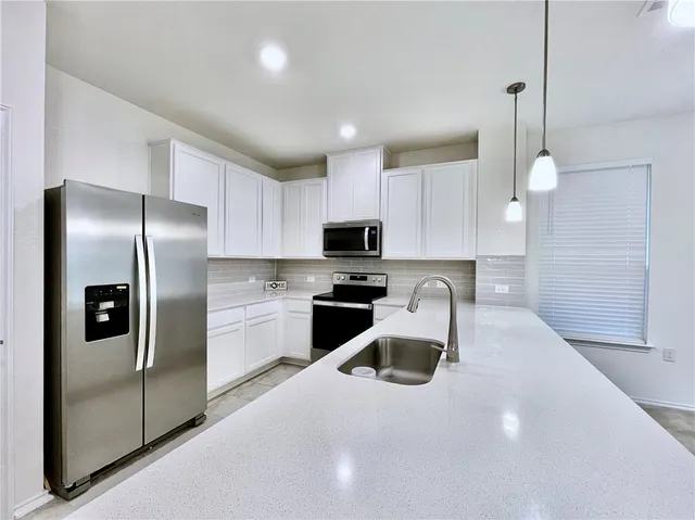 a kitchen with granite countertop a refrigerator a sink a stove and oven with wooden floor