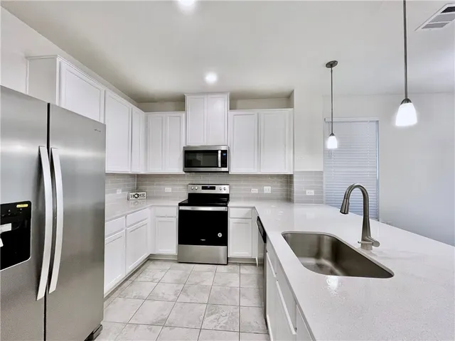 a kitchen with stainless steel appliances granite countertop a sink a stove a refrigerator and cabinets