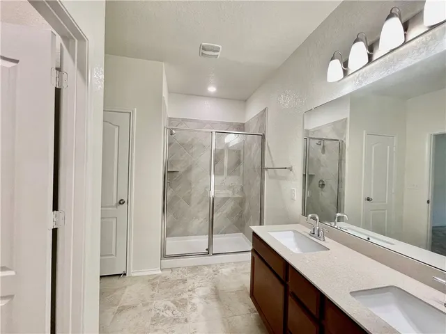 a bathroom with a double vanity sink mirror and shower
