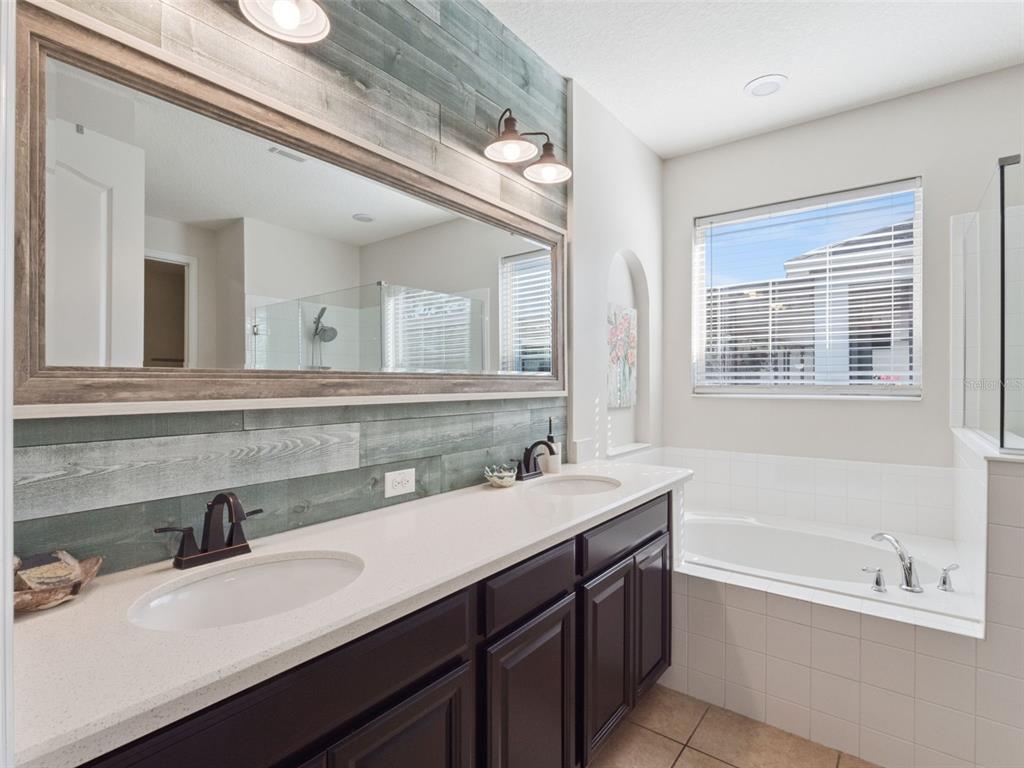 1025 Sadie Ridge Road Clermont, FL 34715 - Photo 24 of 50 a bathroom with a sink double vanity granite tub shower and a mirror