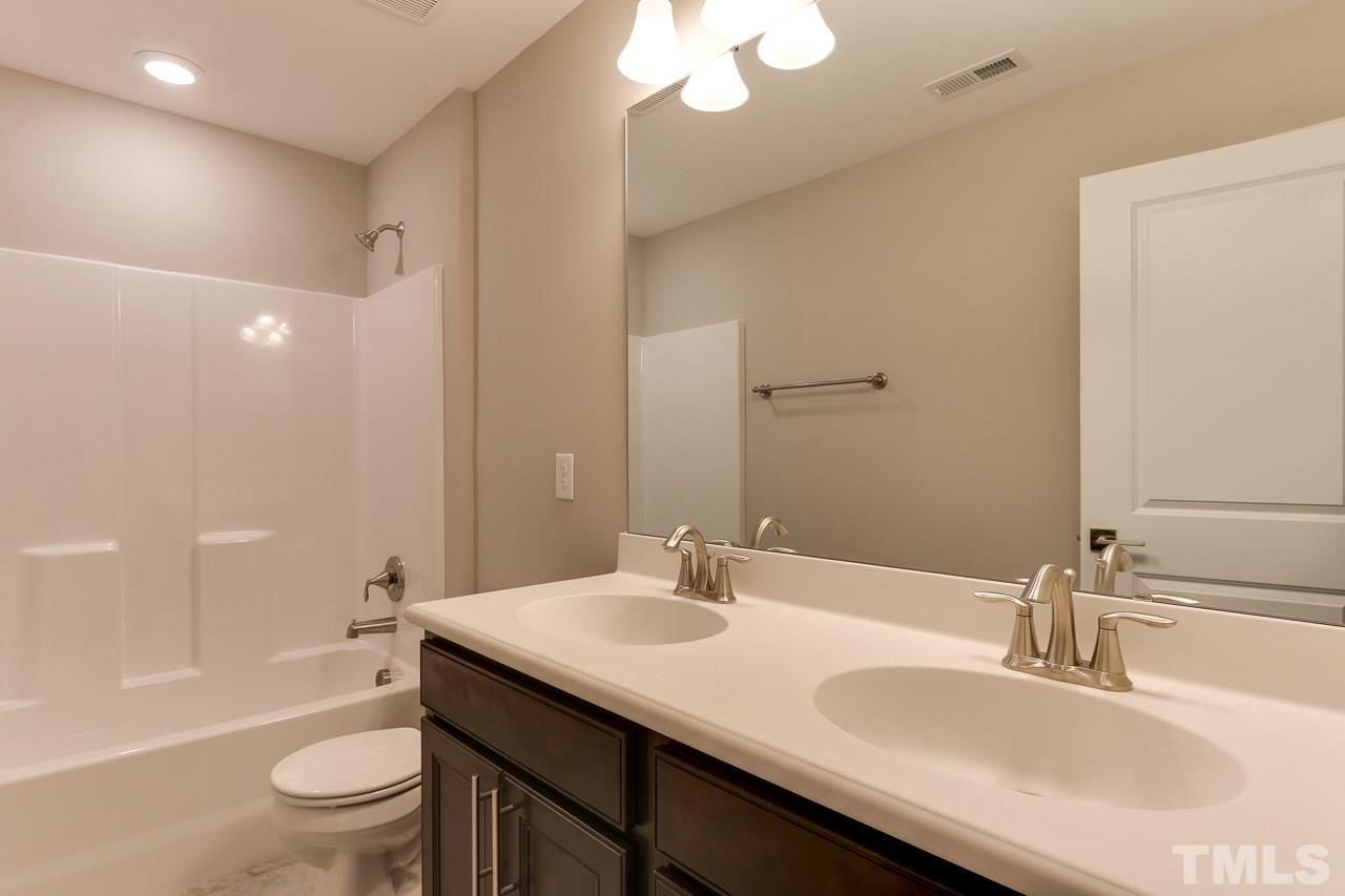 504 Cristobal Street, Unit 134 Rolesville, NC 27571 - Photo 26 of 30 a bathroom with a granite countertop sink a toilet and a large mirror