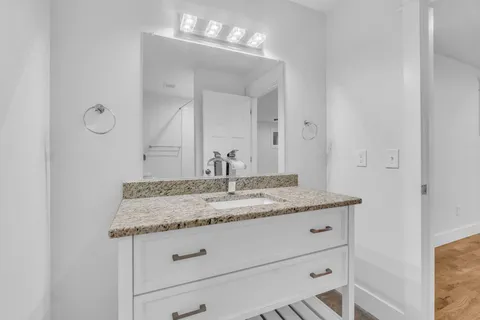 a bathroom with a granite countertop sink and a mirror