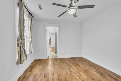 an empty room with wooden floor closet and windows