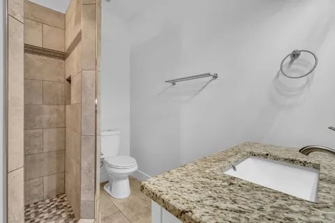 a bathroom with a granite countertop sink a toilet and a shower