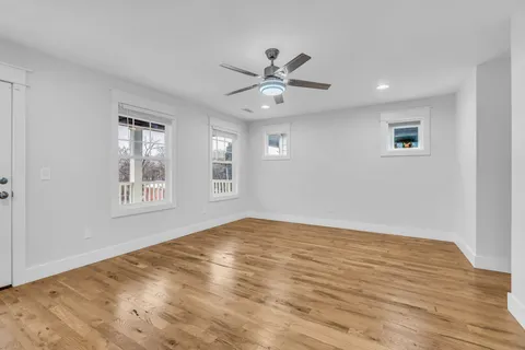 a view of an empty room with window and wooden floor