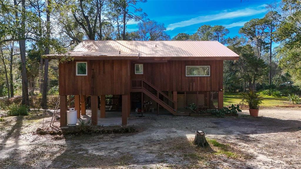 3490 Southeast 193rd Place Yankeetown, FL 34498 - Photo 53 of 71 a view of a wooden house with a small yard and large tree
