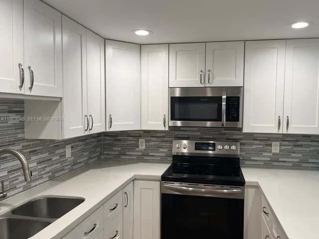 a kitchen with granite countertop a sink a stove and cabinets