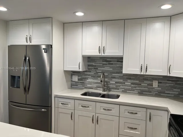 a kitchen with appliances a refrigerator and cabinets