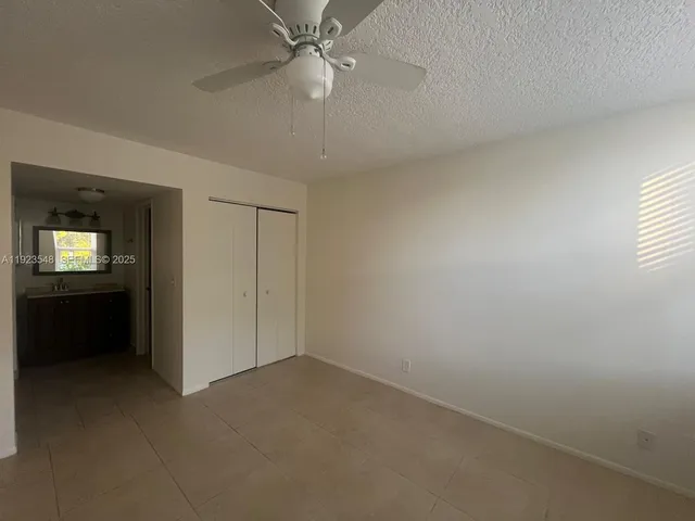 an empty room with a bathroom and a ceiling fan