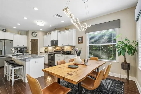 a kitchen with refrigerator a stove a dining table and chairs with wooden floor