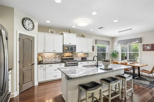 a kitchen with stainless steel appliances granite countertop a stove top oven a refrigerator a sink and a stove with wooden floor