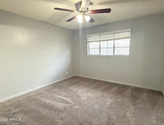 an empty room with a window and a ceiling fan