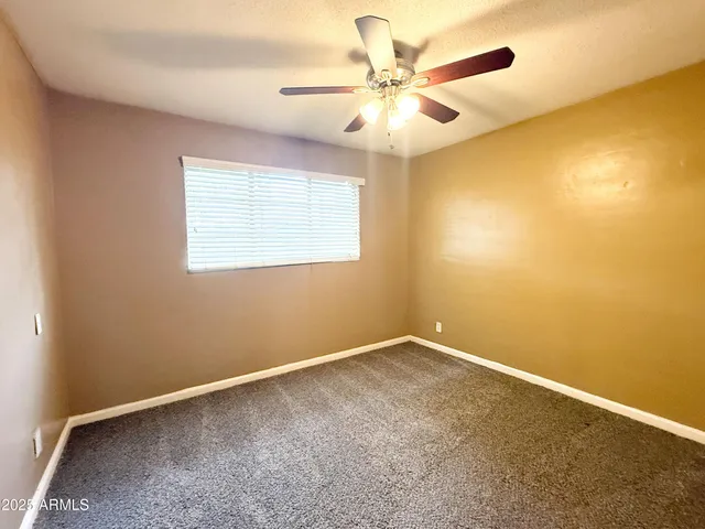 an empty room with a chandelier fan and windows