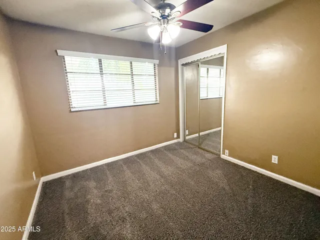 an empty room with a window and a fan
