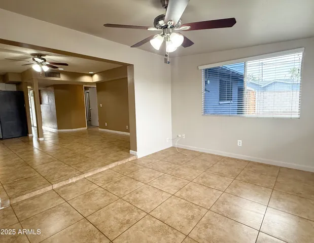 a view of an empty room with window and chandelier fan