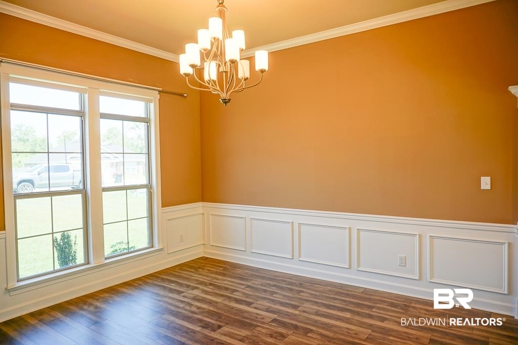 593 Begeman Road Mobile, AL 36608 - Photo 9 of 23 Empty room with dark hardwood / wood-style flooring, a chandelier, and crown molding