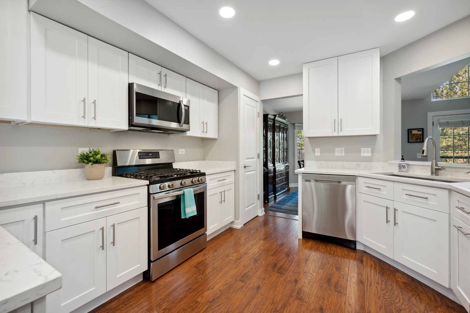 27W204 Chelsea Circle Winfield, IL 60190 - Photo 6 of 30 a kitchen with stainless steel appliances granite countertop white cabinets a sink a stove a microwave and wooden floors