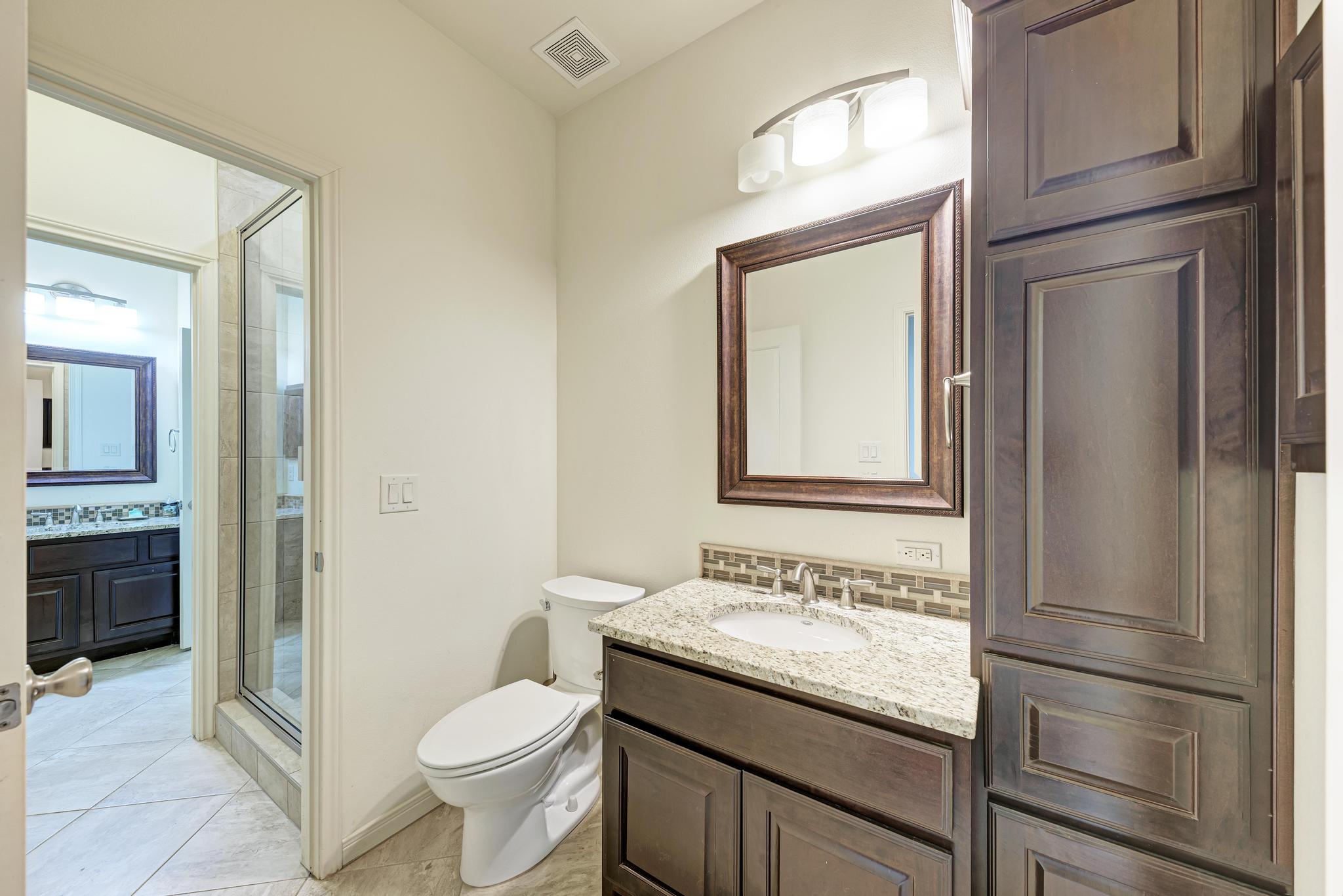 2605 Indian Creek Road Austin, TX 78734 - Photo 23 of 33 Bathroom featuring a dark wood-finish vanity with a light speckled countertop, an integrated sink, and a framed mirror