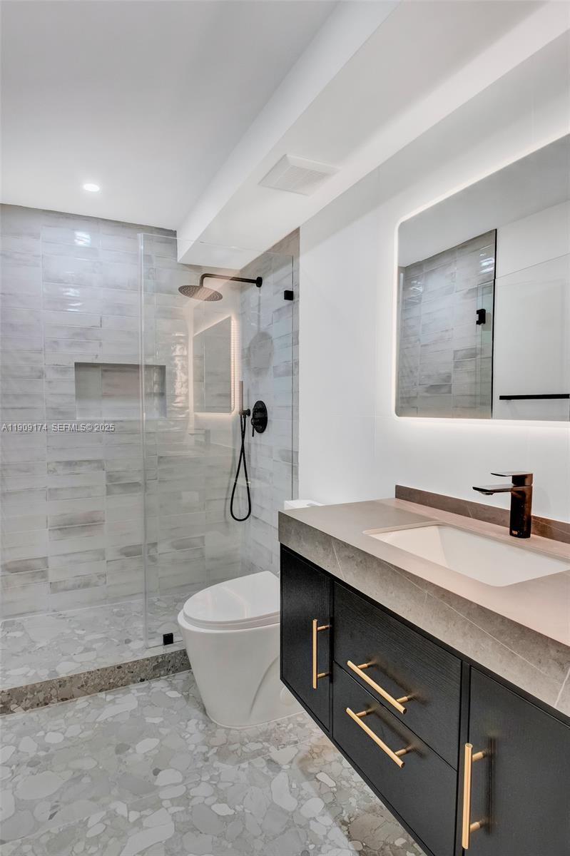 54 Isle Of Venice Drive, Unit 7 Fort Lauderdale, FL 33301 - Photo 28 of 41 a bathroom with a granite countertop sink a toilet a mirror and shower