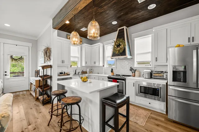 a kitchen with stainless steel appliances a stove a sink dishwasher and a refrigerator with wooden floor