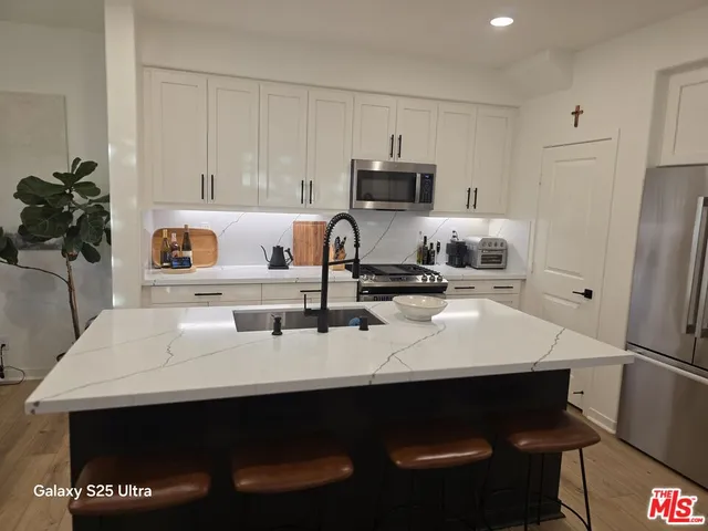 a kitchen with stainless steel appliances a sink cabinets and wooden floor