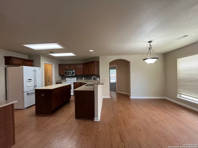 a view of kitchen with refrigerator stove and wooden floor
