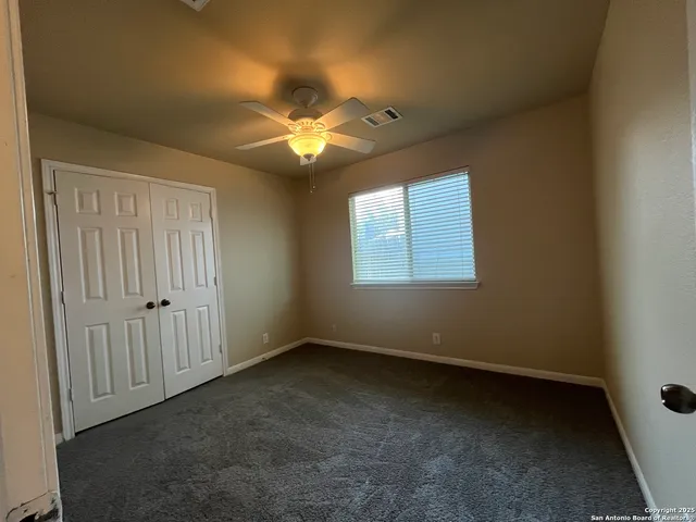 an empty room with a chandelier fan and a window