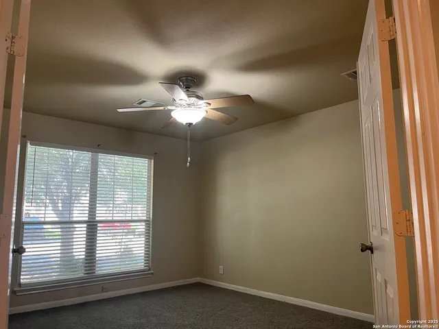 en empty room with windows and chandelier fan