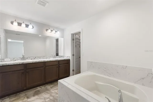 a spacious bathroom with a tub sink and mirror