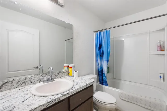 a bathroom with a granite countertop sink toilet a mirror and shower