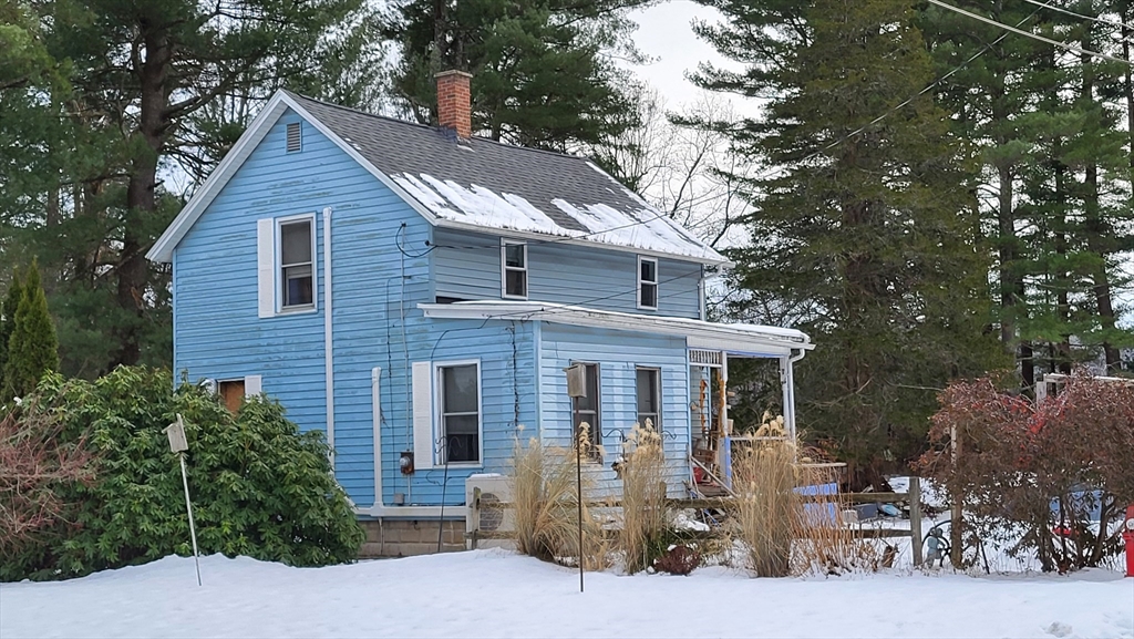 a front view of a house with yard and trees in the background