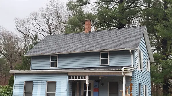 a front view of a house with a tree