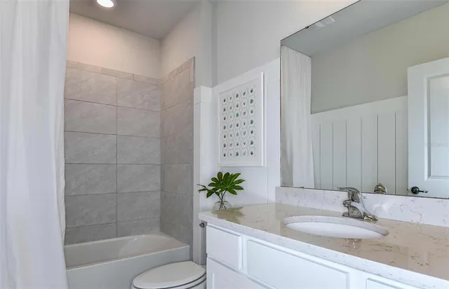 a bathroom with a granite countertop sink a toilet and shower