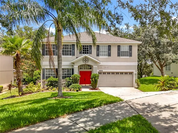a view of a house with a small yard and palm trees