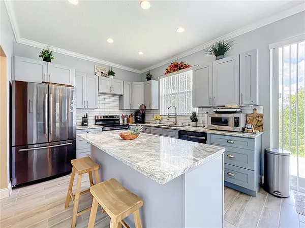 a kitchen with granite countertop a refrigerator a stove a sink dishwasher and wooden cabinets with wooden floor