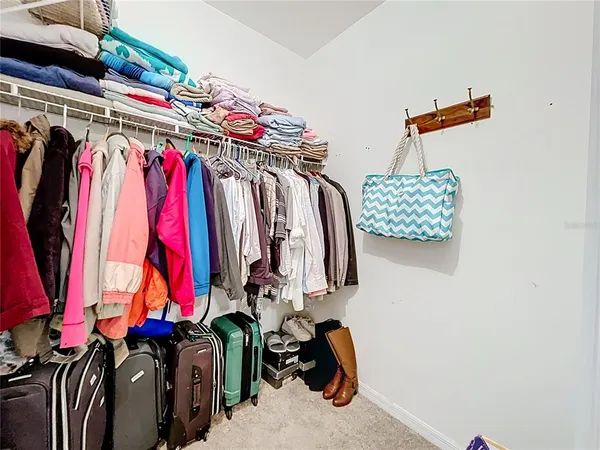 a view of walk in closet with clothes and shoes