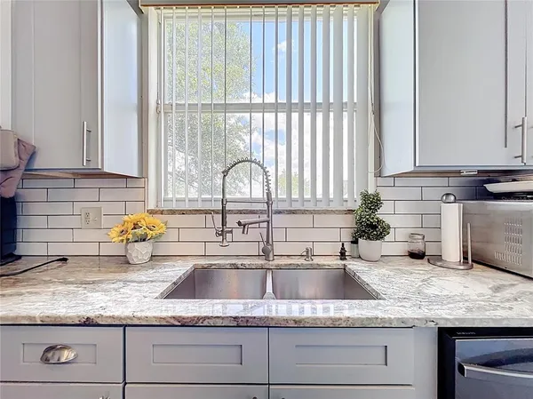 a kitchen with granite countertop a stove sink and cabinets