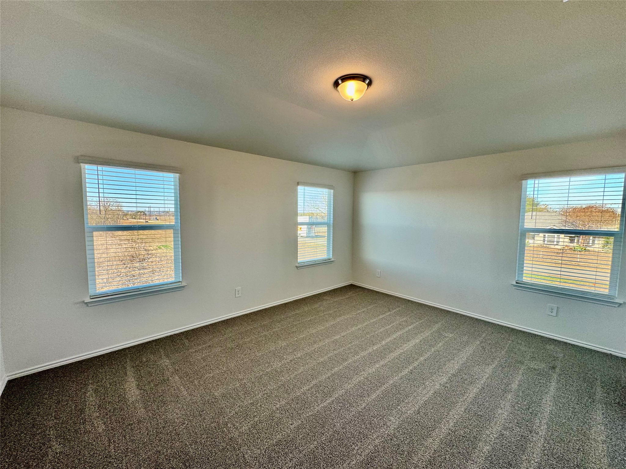 104 Calcite Road, Unit 1 Kyle, TX 78640 - Photo 3 of 7 Empty room featuring healthy amount of natural light, dark carpet, and a textured ceiling
