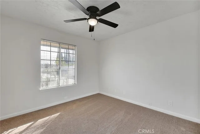 an empty room with a window and a fan