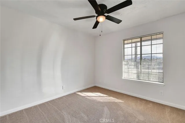an empty room with a window and a fan