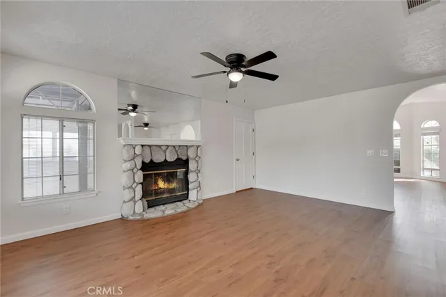 an empty room with windows fireplace and wooden floor