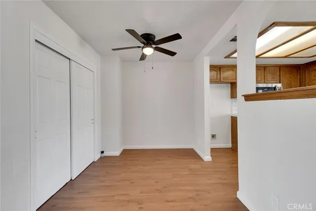 a view of an empty room with wooden floor and a ceiling fan