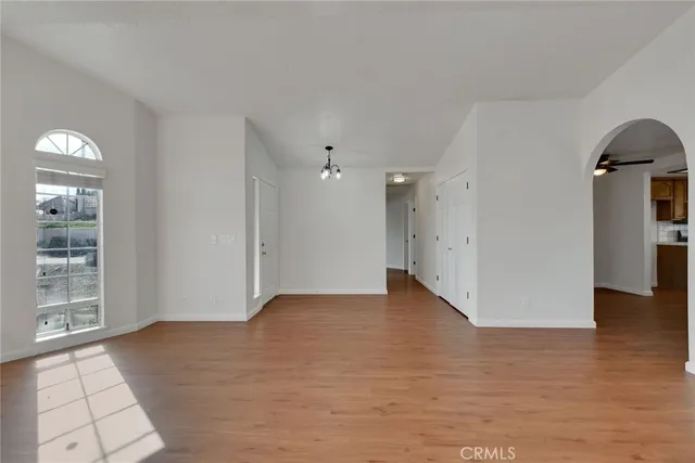 a view of an empty room with window and wooden floor