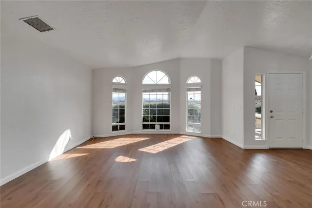 a view of a big room with wooden floor and a window