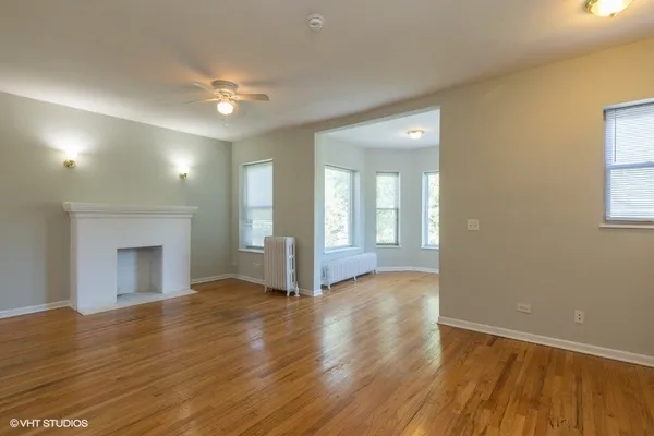 a view of an empty room with wooden floor and a fireplace