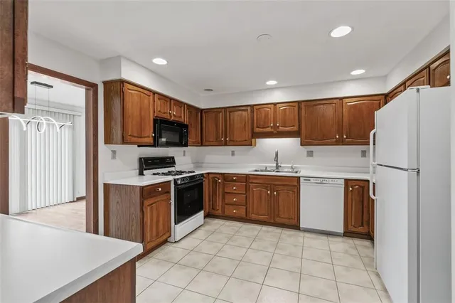 a kitchen with granite countertop a refrigerator stove top oven and sink