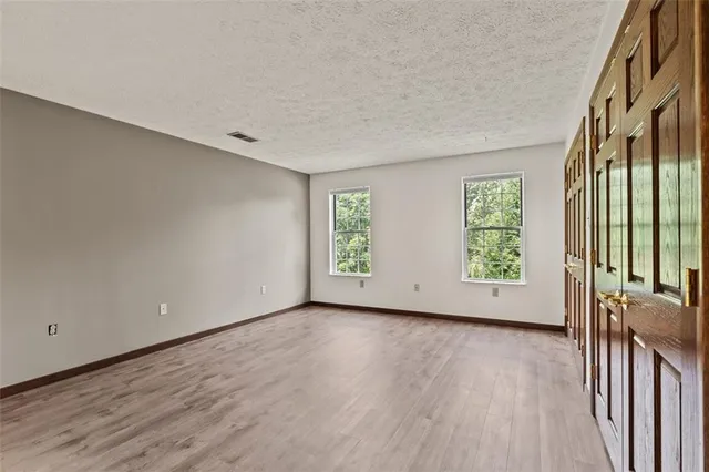 an empty room with wooden floor and windows