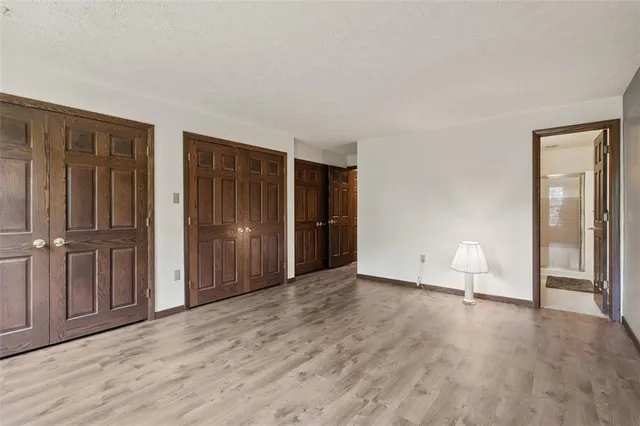 a view of an empty room with wooden floor and a cabinet