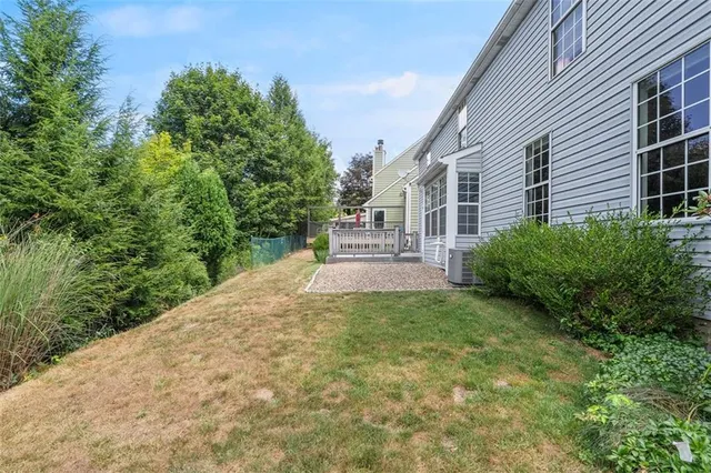 a view of a yard in front of a house with plants and large tree