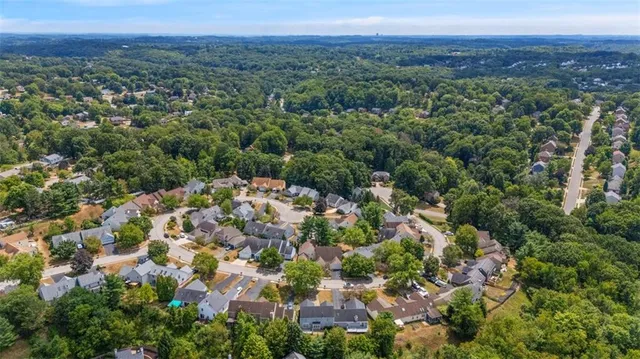 an aerial view of residential houses with outdoor space and trees all around